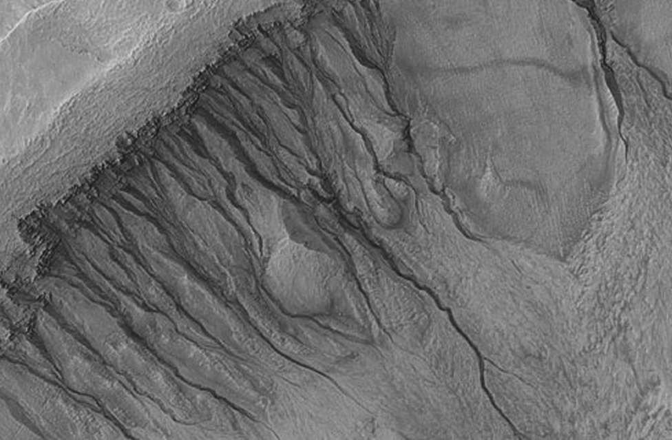 a 牛顿坑（Crater Newton）坑壁上的冲沟和其他地貌特征，可能是干冰块滑坡时留下的