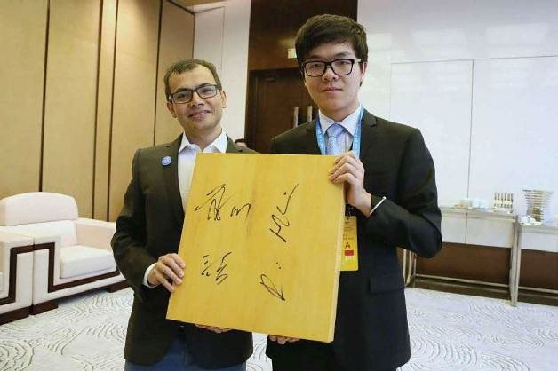 2017年在中国，DeepMind的联合创始人兼CEO德米斯·哈萨比斯（Demis Hassabis，左）和柯洁在历史性的围棋比赛结束后会面，共同展示带有柯洁签名的棋盘